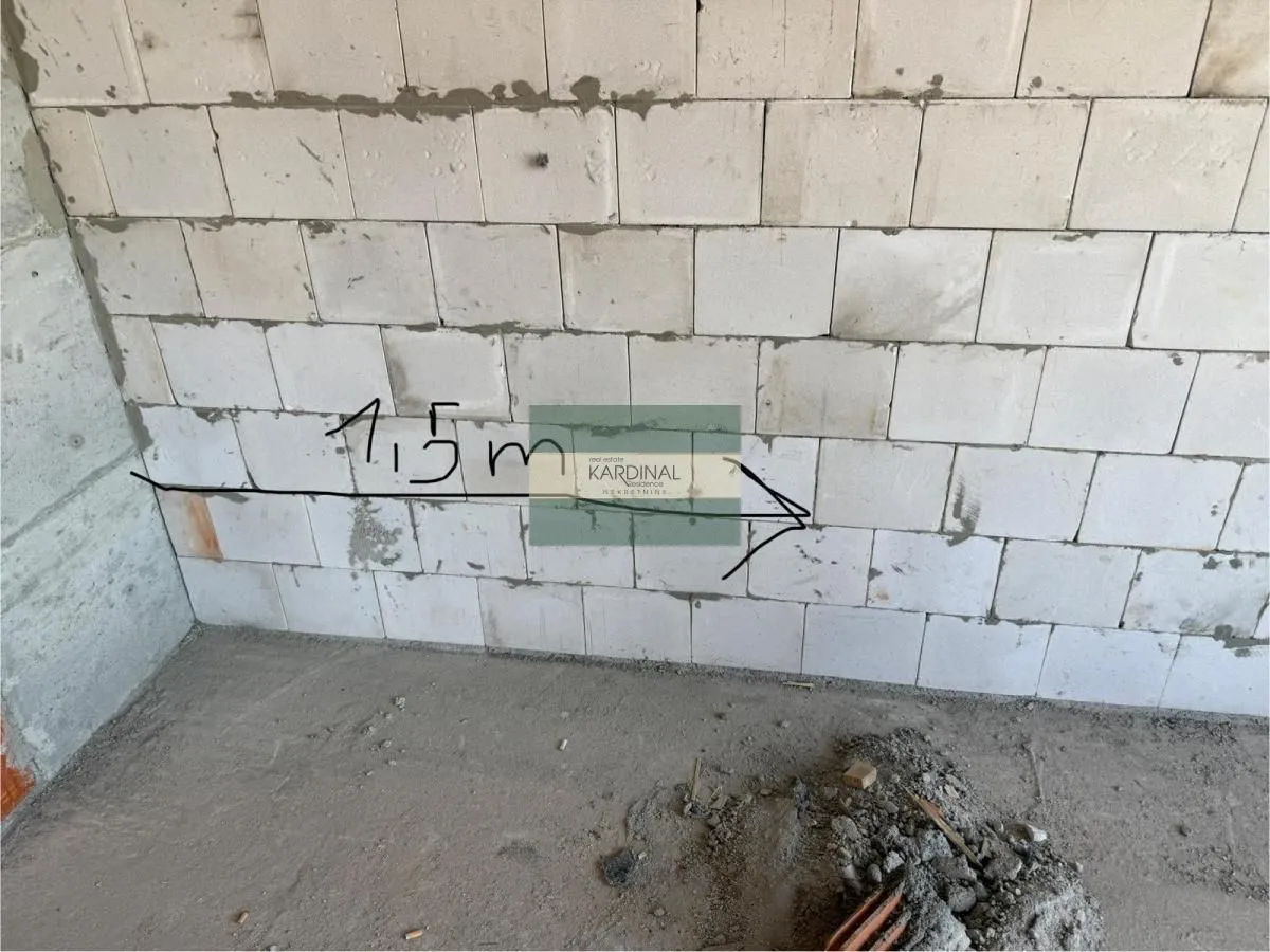 Pogled na zid od cigle u objektu u izgradnji sa ucrtanom merom.