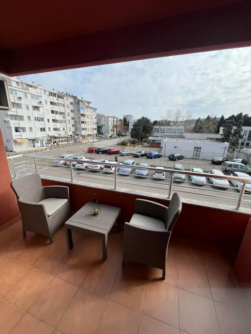 Furnished balcony with seating set and a view of the city street and parking lot.