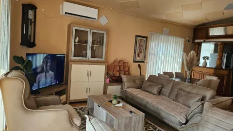 Furnished living room with sofa, television, and dining area in the background. - image 5
