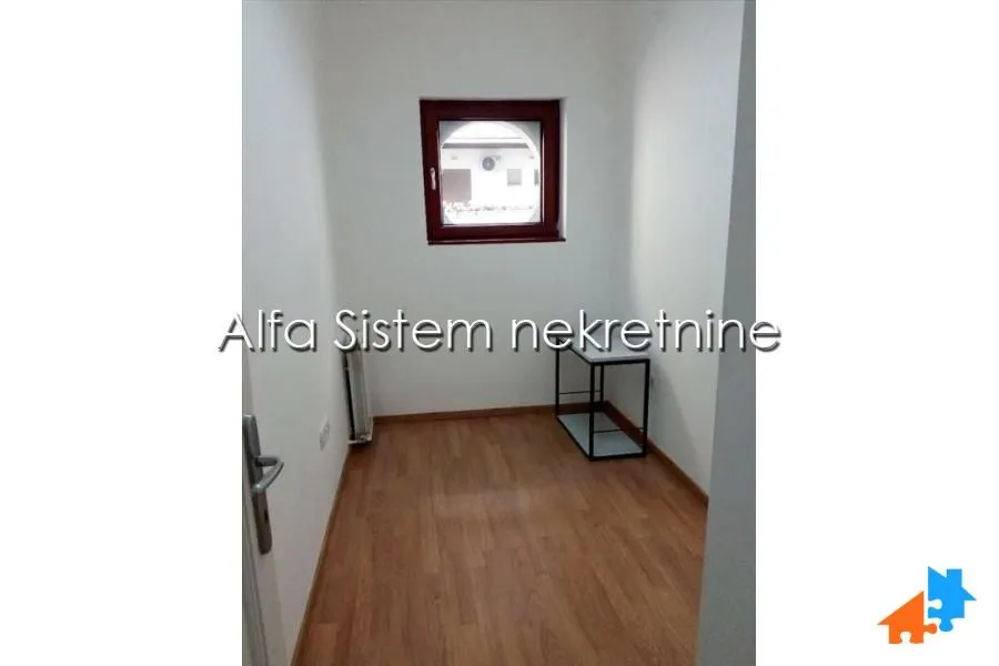 Empty small room with a window and laminate flooring.