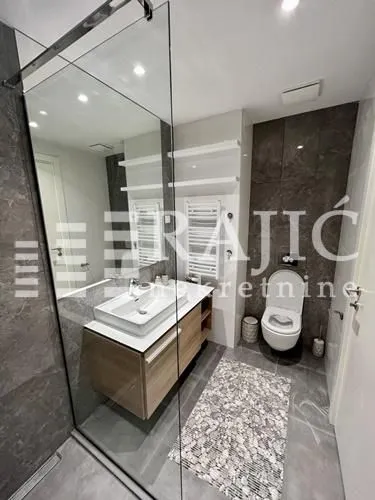 Modern bathroom with a washbasin, walk-in shower, and toilet.