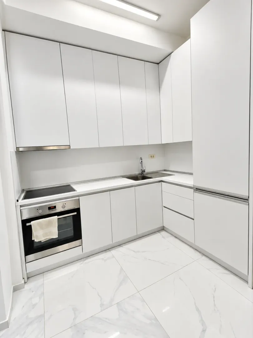 Modern white kitchen with built-in oven and stovetop.