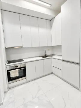 Modern white kitchen with built-in oven and stovetop. - image 2
