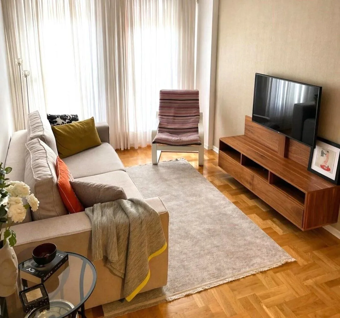 Living room with sofa, TV unit and parquet flooring.