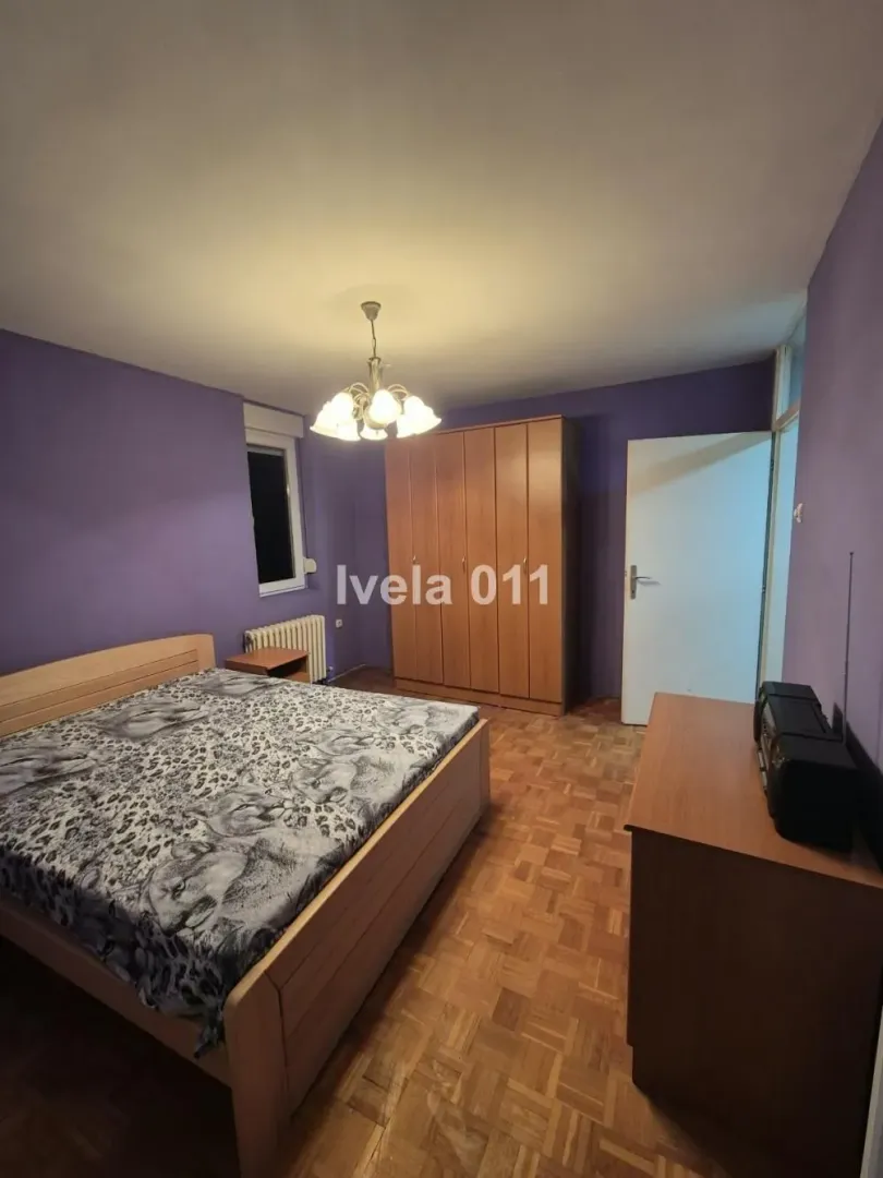 Furnished bedroom with a double bed, wardrobe, and parquet flooring.