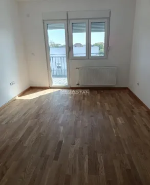 Prazna neopremljena soba sa drvenim podom i balkonskim vratima. - image 3