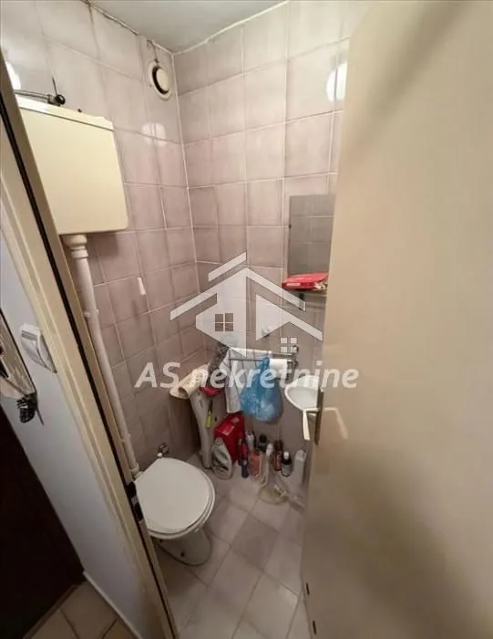 Small bathroom with tiles, toilet, and a small washbasin.