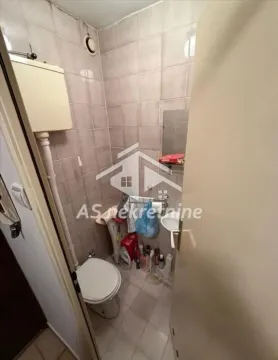 Small bathroom with tiles, toilet, and a small washbasin. - image 16