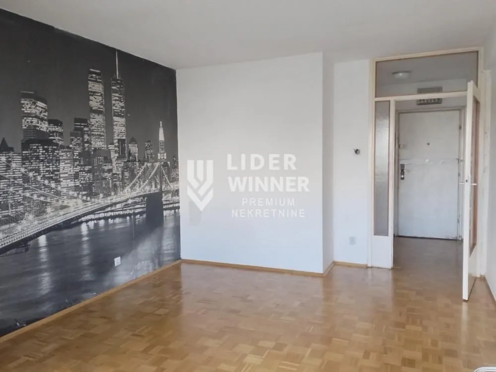 Empty living room with a city-themed wallpaper and parquet flooring.