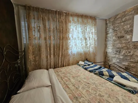 Spavaća soba sa bračnim krevetom, zavesama i zidom od kamena. - image 8