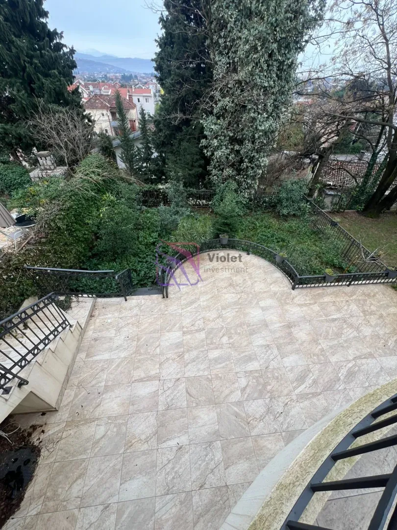 Popločana terasa sa ogradom i pogledom na dvorište i okolinu.