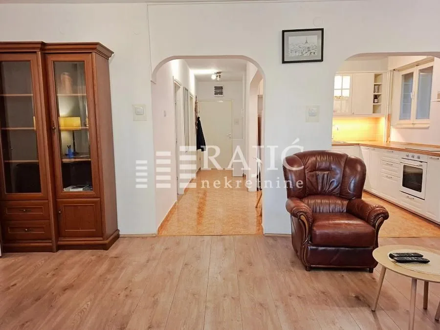 Living room with wooden furniture and a view of the hallway and kitchen.