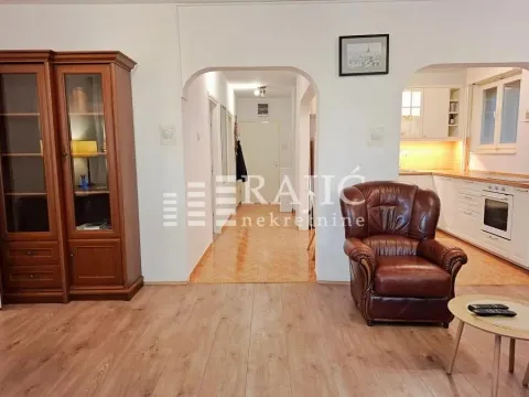 Living room with wooden furniture and a view of the hallway and kitchen. - image 7