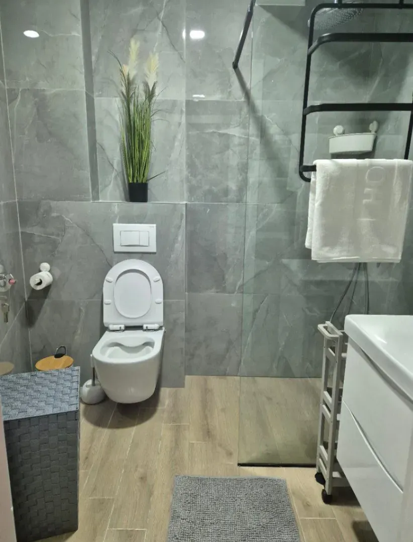 Modernly equipped bathroom with a walk-in shower and grey tiles.