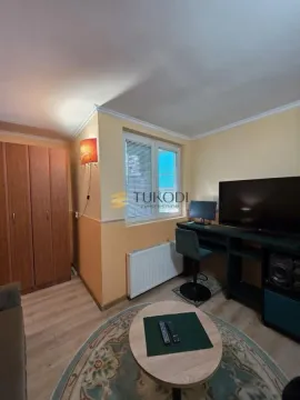 Living room with a desk, television, and wooden wardrobe. - image 4