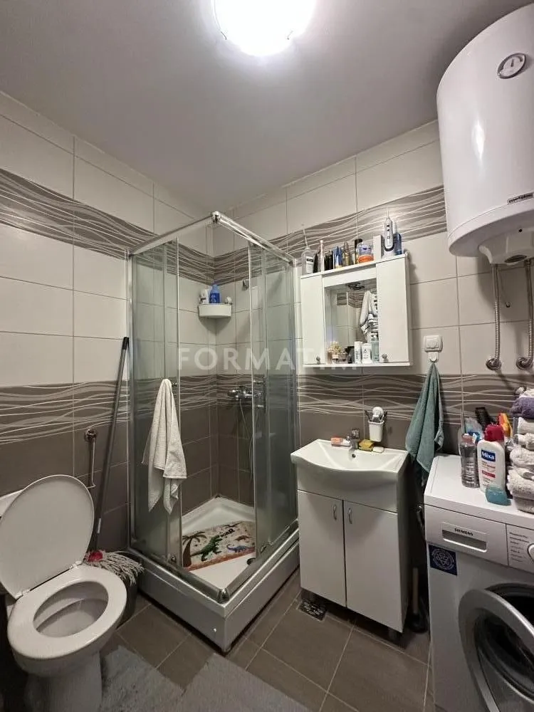 Kupatilo opremljeno tuš kabinom, umivaonikom, WC šoljom i veš mašinom.
