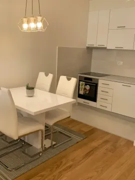 Moderna kuhinja sa bijelim elementima i trpezarijskim stolom. - image 3