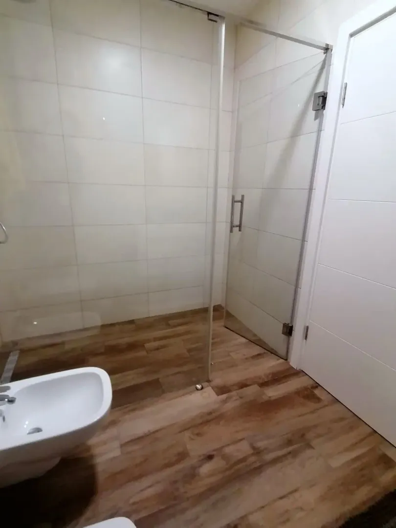 Moderne kupatilo sa tuš kabinom i bijelim keramičkim pločicama.