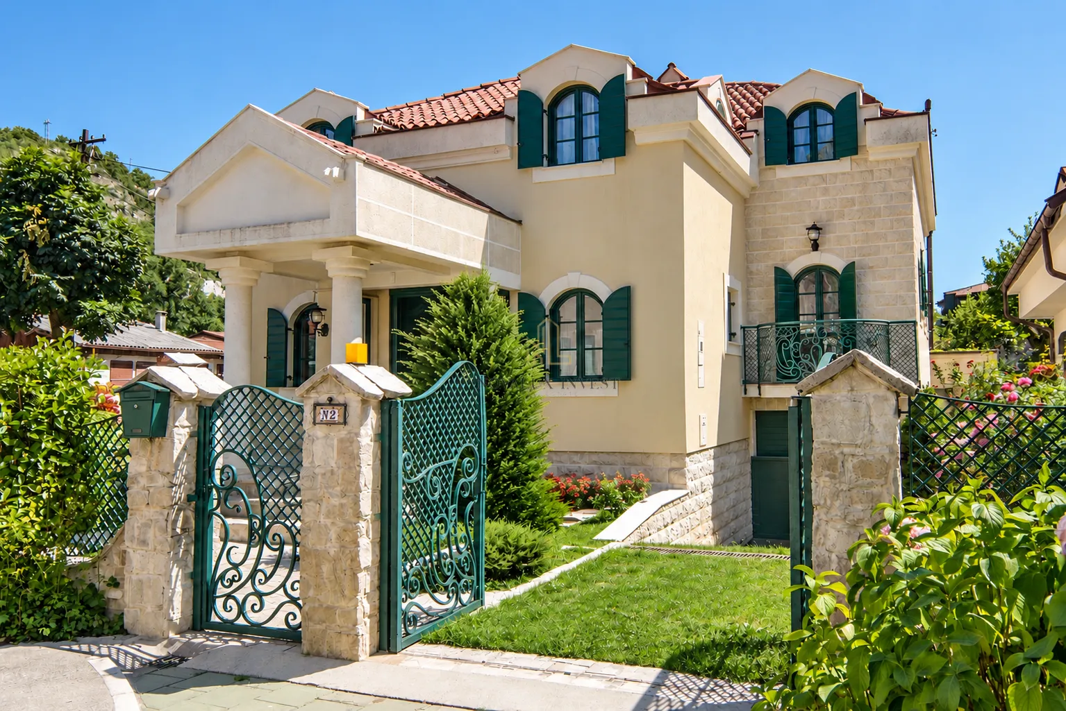 Pogled na prednju fasadu kuće sa dvorištem i ogradom.