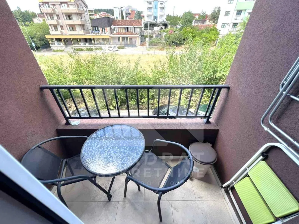 Manji namješten balkon sa stolom i stolicama i pogledom na okolinu.