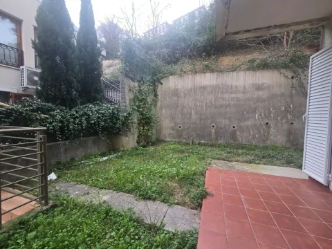 Small grassy yard with a tiled patio area and fence. - image 12