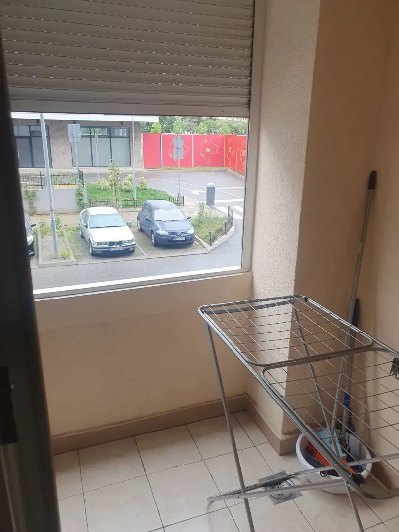 A small balcony with a clothes drying rack and a view of the parking lot.