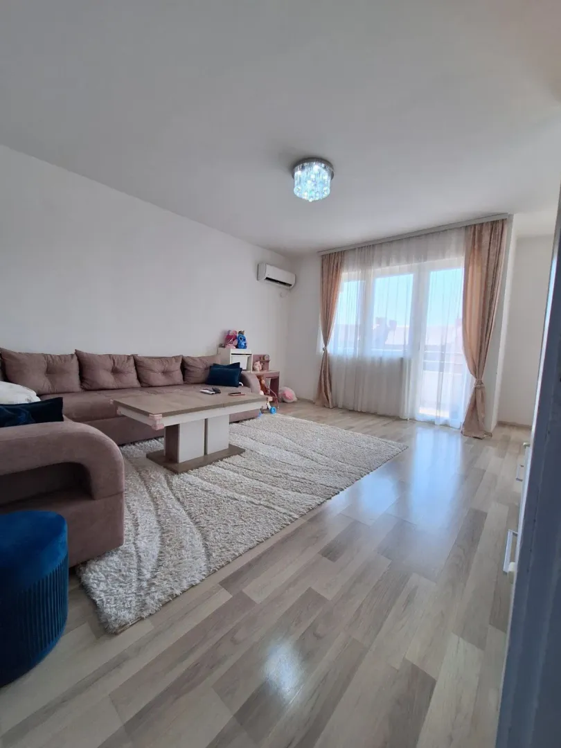 Dnevna soba sa garniturom, stočićem i izlazom na terasu.
