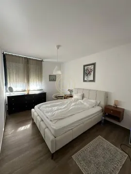 Spavaća soba sa bračnim krevetom, komodom i prozorom sa zavesama. - image 4