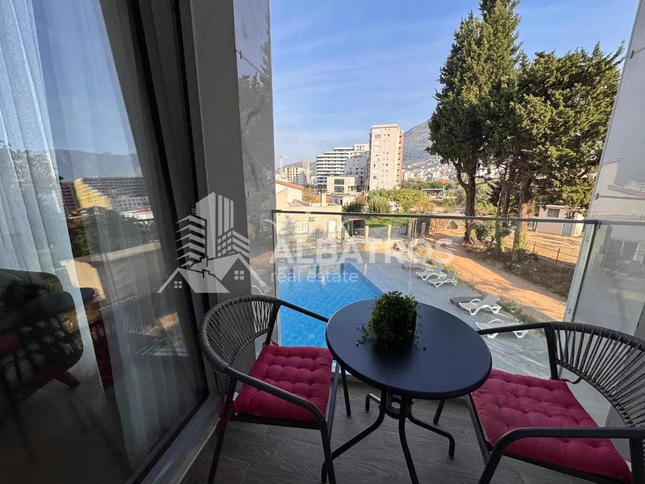 A small furnished balcony with a view of the pool and surroundings.