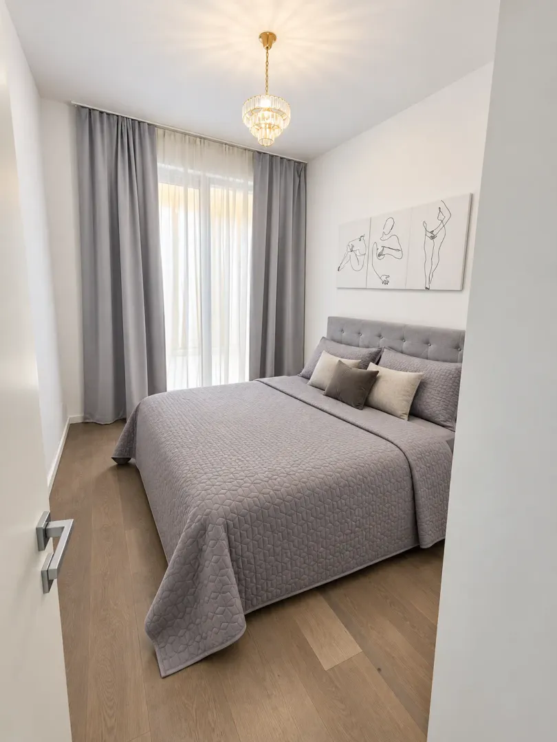 Modern bedroom with a double bed, grey curtains, and decorative lighting.