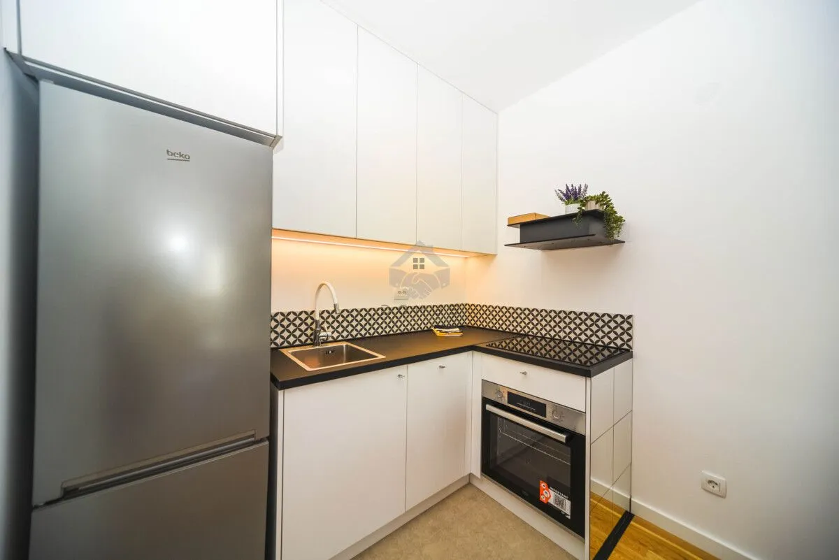 Small modern kitchen with white cabinetry and built-in appliances.