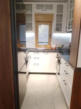 Pogled na moderno opremljenu kuhinju sa belim elementima i ugradnim uređajima. - image 6