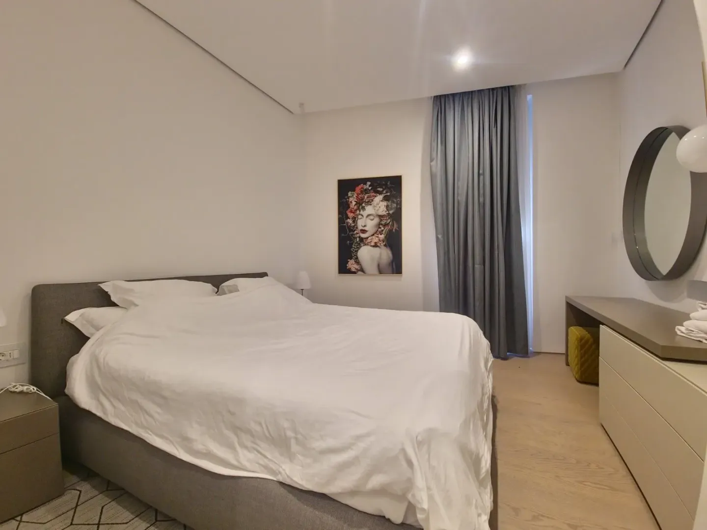 Modern bedroom with a double bed, artwork, and a mirror.