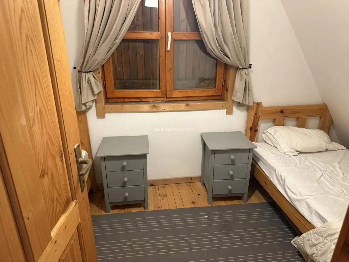 Small bedroom with a bed, two bedside tables, and a window.