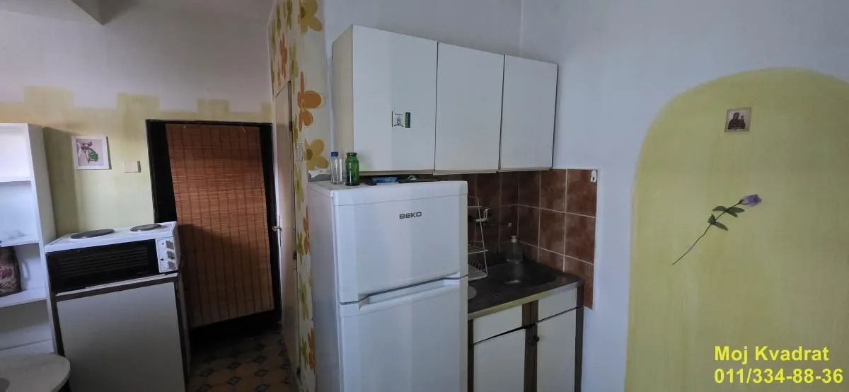 Manja kuhinja sa belim elementima i frižiderom.