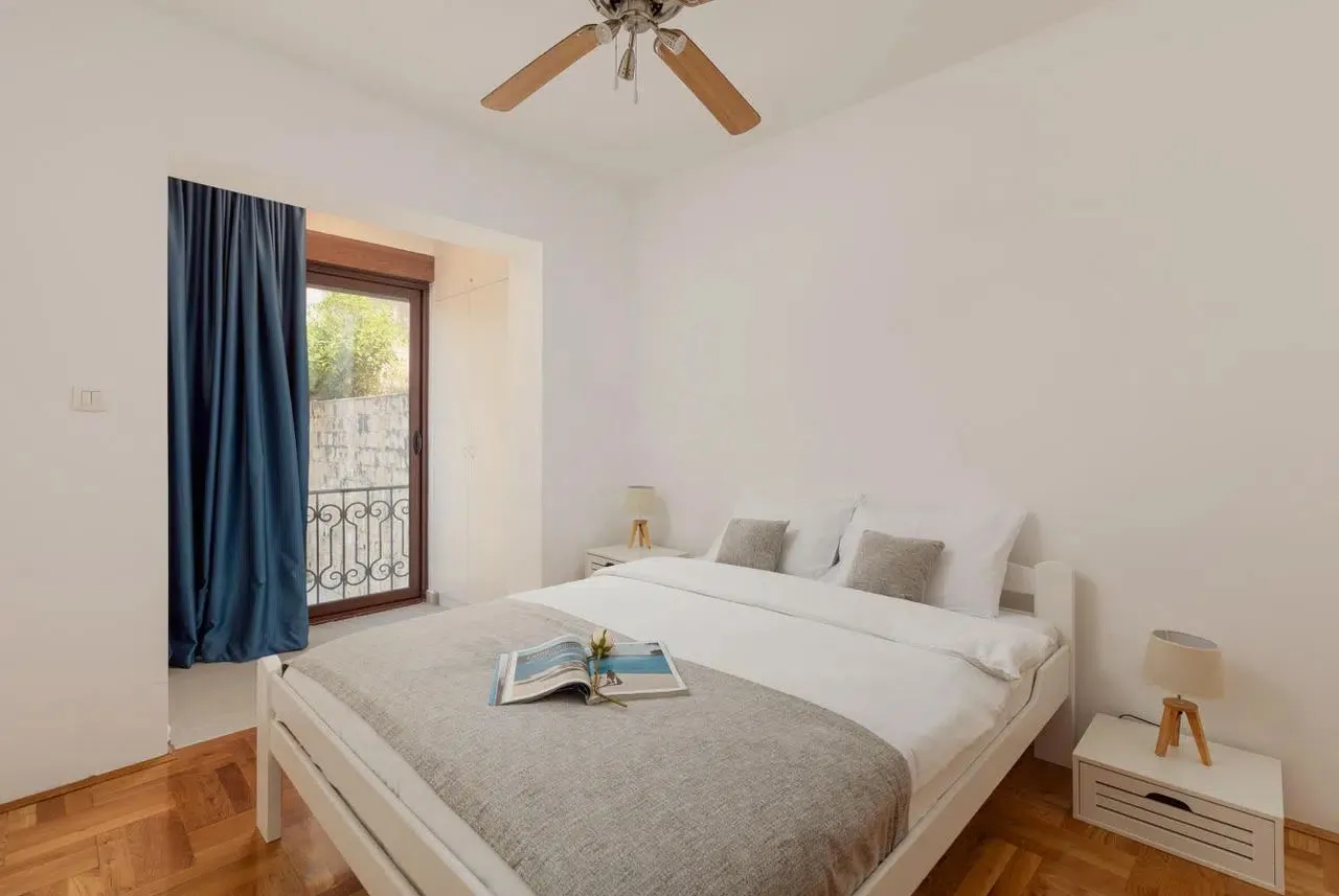 Bright bedroom with a white bed and access to the terrace.