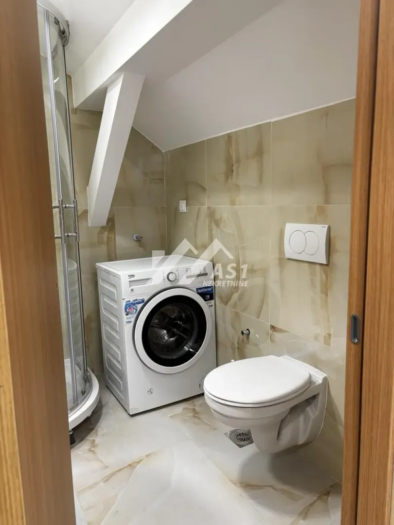 Manje kupatilo sa tuš kabinom, wc šoljom i veš mašinom.
