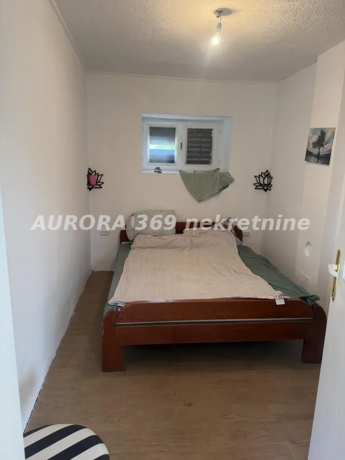 Manja spavaća soba sa drvenim krevetom i prozorom.
