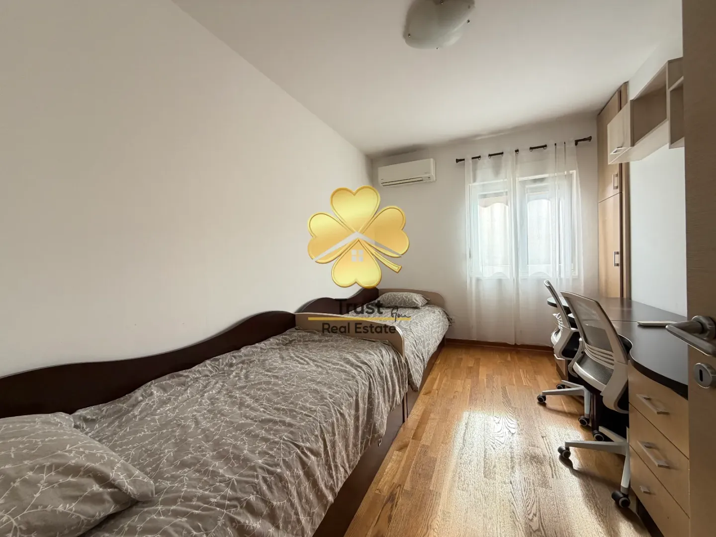 Furnished bedroom with two beds and a desk.