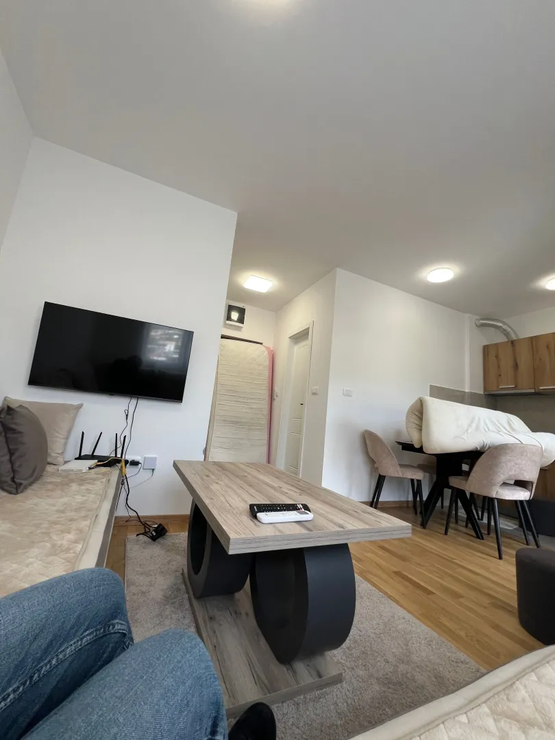 Living room with a sofa, coffee table and wall-mounted TV.