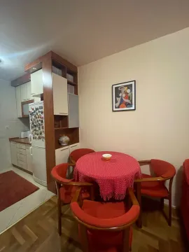Trpezarija sa okruglim stolom i crvenim stolicama, povezana sa kuhinjom. - image 2