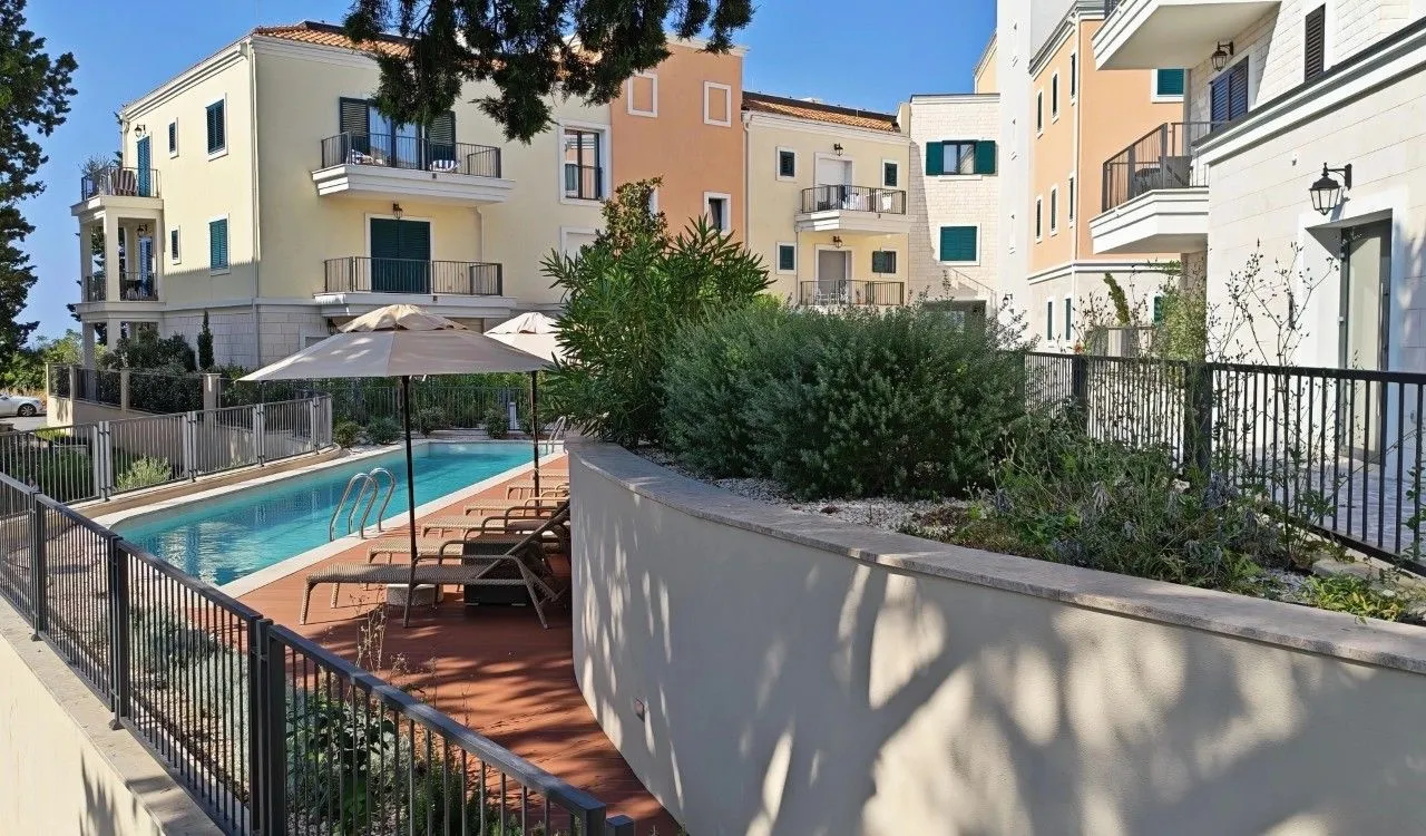 Pogled na vanjski bazen i dio stambenog kompleksa sa zelenilom.