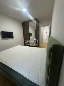 Nameštena spavaća soba sa bračnim krevetom, garderoberom i televizorom na zidu. - image 6