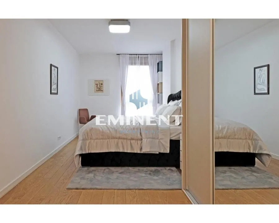 Furnished bedroom with a double bed, wooden flooring, and a large mirrored wardrobe.