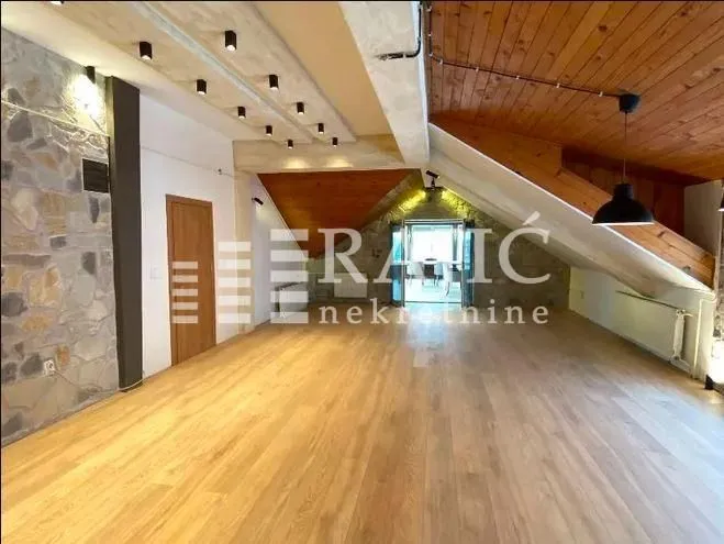 Spacious living room with wooden flooring and a sloped ceiling.