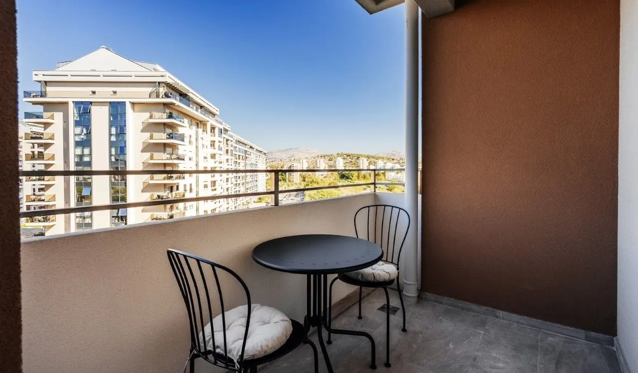 Covered balcony space with a small table and two chairs and a view of surrounding buildings.