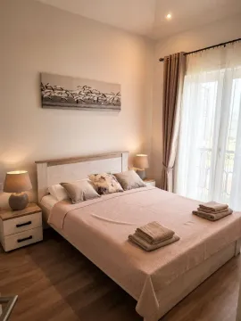 Svijetla spavaća soba sa bračnim krevetom, noćnim stočićima i balkonskim vratima. - image 4