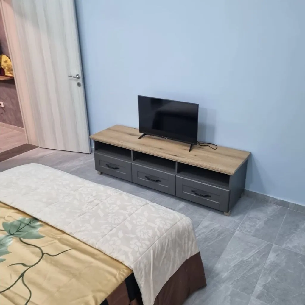 Spavaća soba sa krevetom i komodom za televizor.
