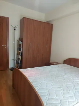 Spavaća soba sa bračnim krevetom, drvenim ormarom i parketom na podu. - image 6