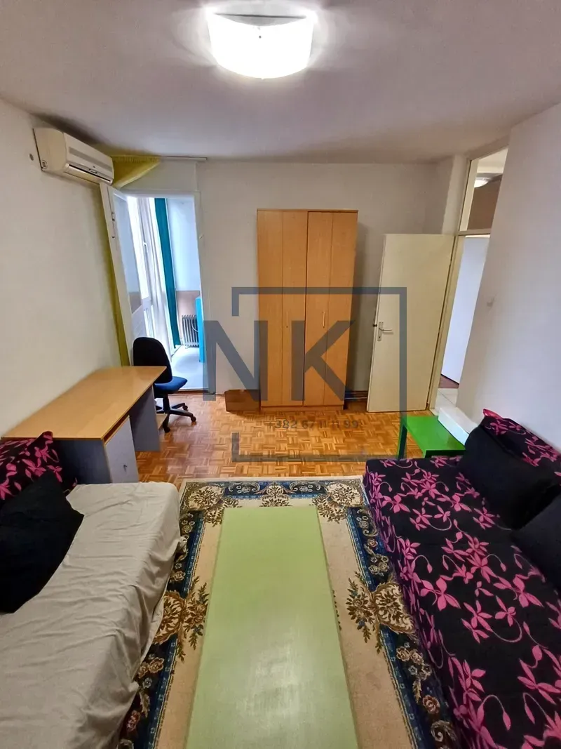 Furnished bedroom with two beds, a desk, and a wardrobe.